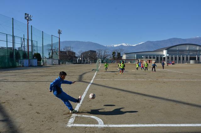 サッカー初蹴り大会で勢いよくボールを蹴る少年の写真