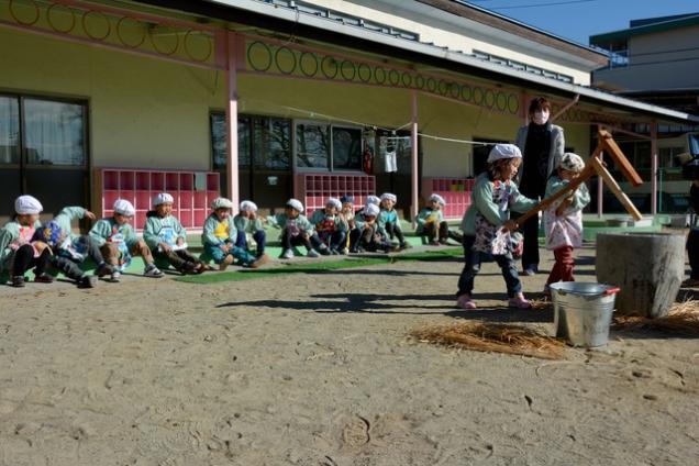 もちをつく園児と周りに座って応援する園児たちの写真