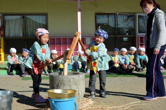 もちをつく園児と周りに座って応援する園児たちの写真