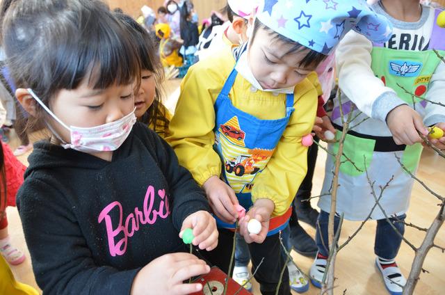 枝に団子を刺して飾り付けをする園児たちの写真