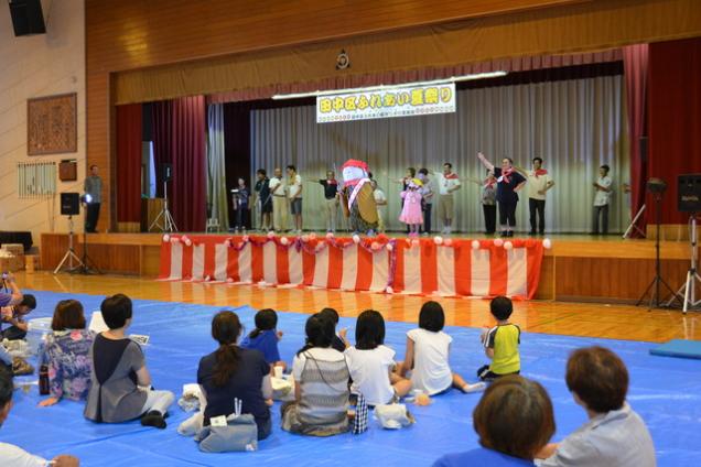 ステージでキャラクターと参加者が踊っている写真