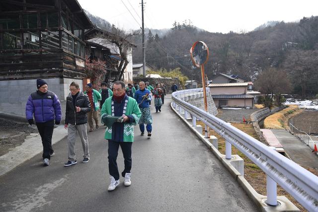 緑の法被を着た保存会の男性たちが町の中を歩いている写真