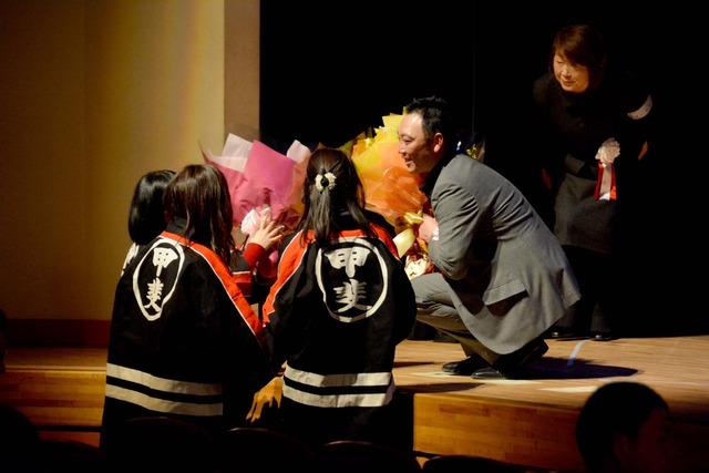 双葉ふれあい文化館にてカラオケ大会で 応援の方が舞台へお花を渡している写真