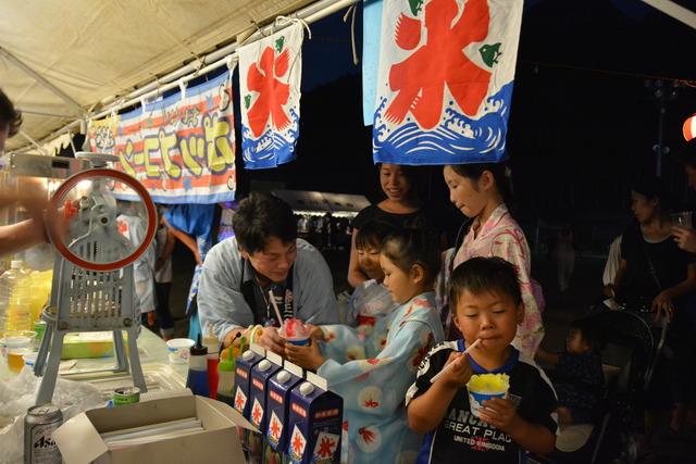 露店でかき氷を食べる子ども達の写真