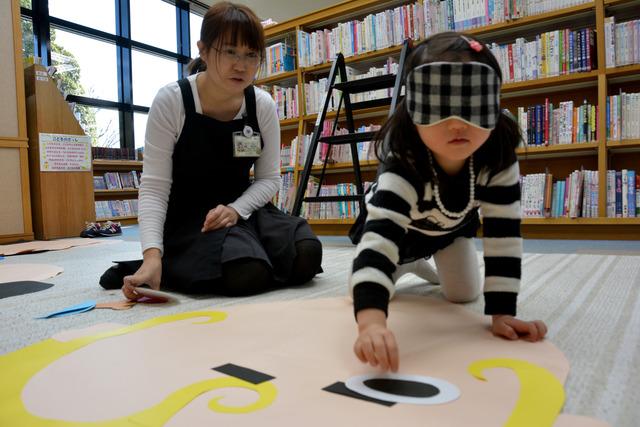 竜王図書館にて目隠しをしながら巨大ふくわらいをしている女の子の写真