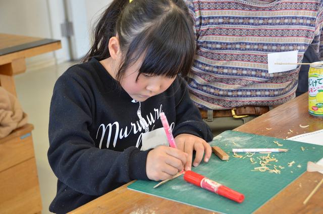 竹とんぼにペンで絵を書く女の子の写真