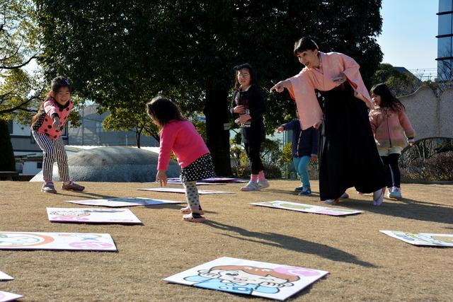 甲州弁ビックかるたに参加している女の子が一つのかるたを取ろうとしている写真