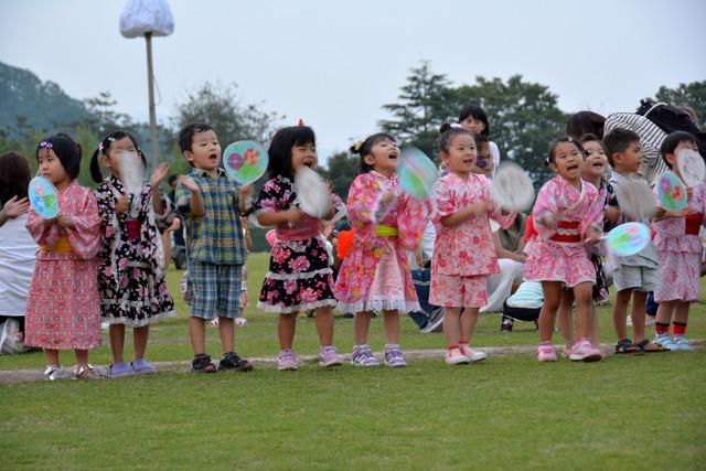 浴衣を着た子どもたちが団扇を叩いて踊っている写真