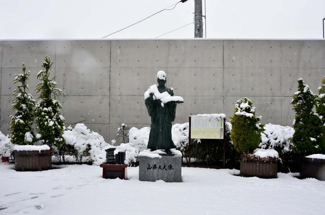 雪で覆われている竜王駅にある山県大弐像の写真