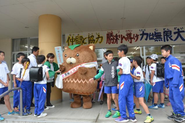 (写真)玄関に集まった児童たちがやはたいぬを囲んでいる様子