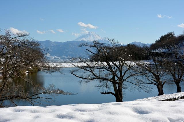 雪がつもっている矢木羽湖の向こうに山が見えている写真
