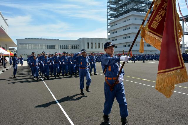(写真)ラッパ隊の演奏により団旗を先頭に入場する団員
