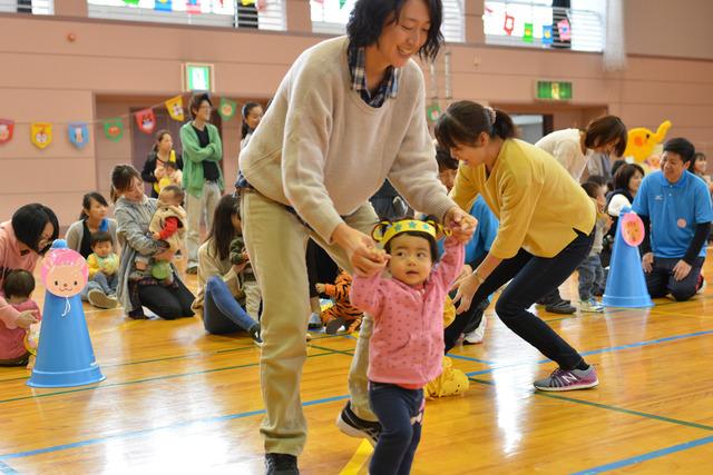 小さな女の子が母親と手を繋いで歩いている写真