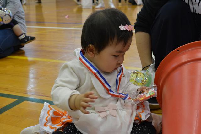 小さな女の子が首にかけられたメダルを見つめている写真