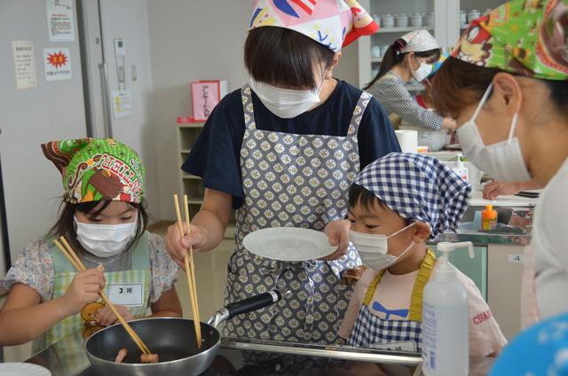 ウィンナーをフライパンで炒める親子の写真