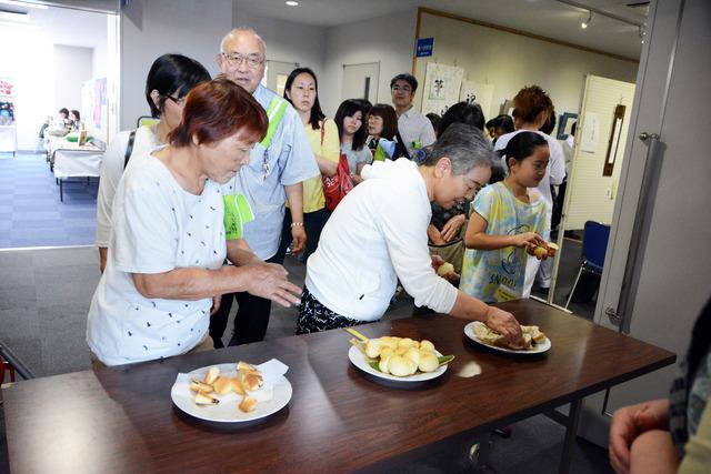 人たちが机の上のパンを試食している写真