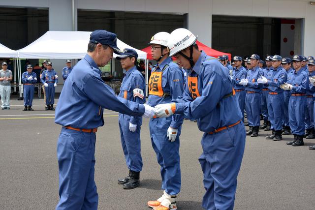 (写真)解散式にて団長から記念記章が手渡される団員