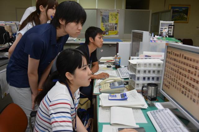 (写真)パソコンに向かい写真の選定をする職員と大学生