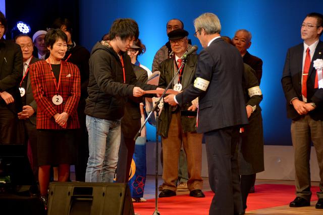 (写真)大会実行委員長から表彰を受ける山本さん