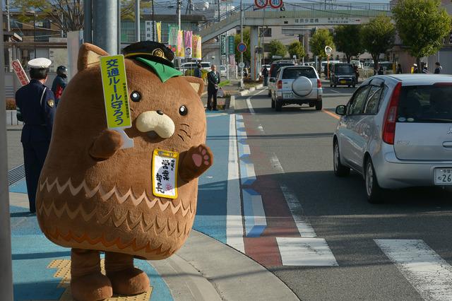 沿道に立ち手を振る甲斐市の営業部長「やはたいぬ」の写真