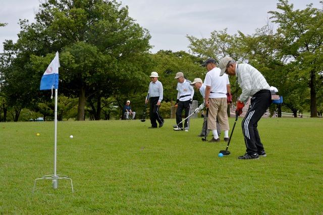 芝生の上でグラウンドゴルフを楽しむ男性の参加者たちの写真