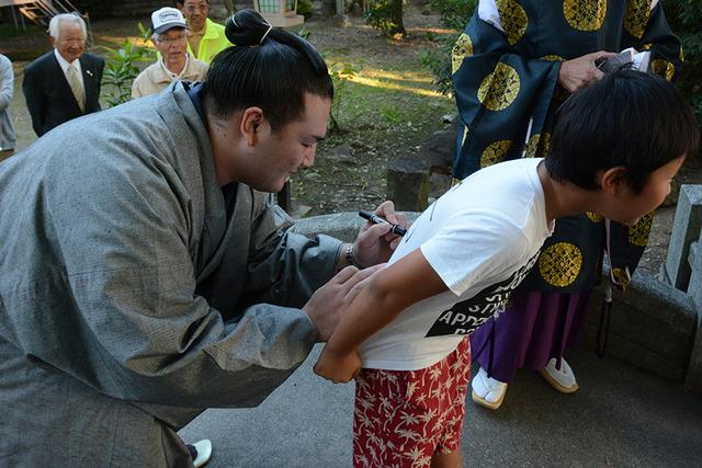 子どもの背中にサインをする竜電の写真