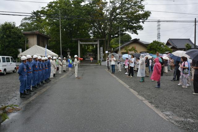 (写真)拡声器を使用する人と集まる住民