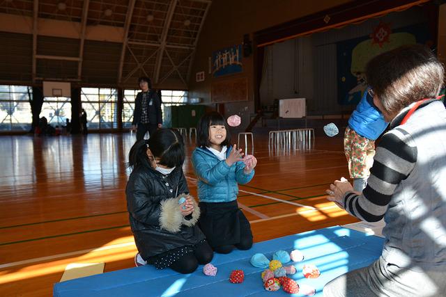 先生に教わりながら、楽しそうにお手玉で遊ぶ女子児童たちの写真