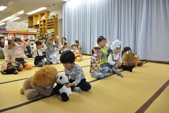 ぬいぐるみと一緒に手遊びをしている子どもたちの写真