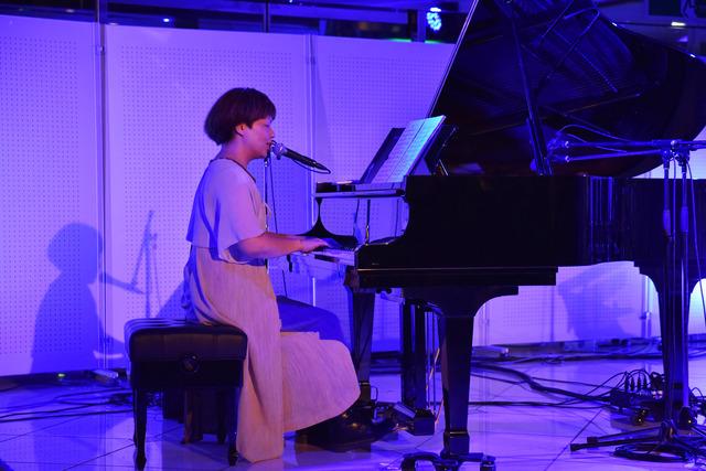 ライトアップされた舞台でピアノを演奏する「チャンティー」さんの写真