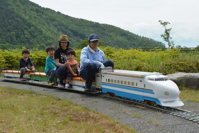 小さなSL列車に母親、3人の子どもが乗っている写真