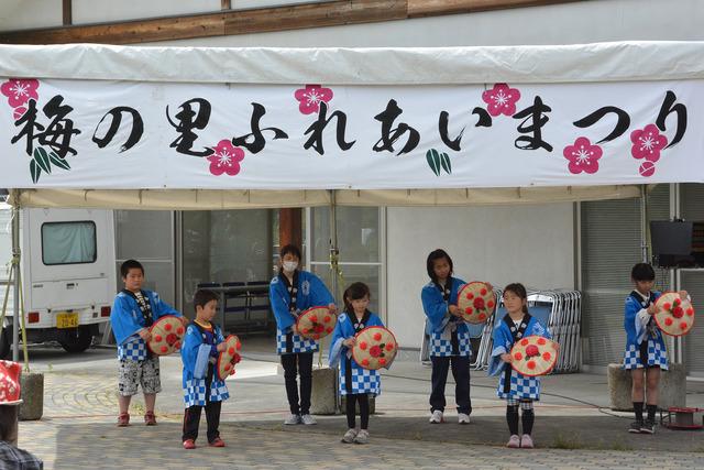 屋外ステージで青い法被を着た子どもたちが花笠音頭を披露している写真