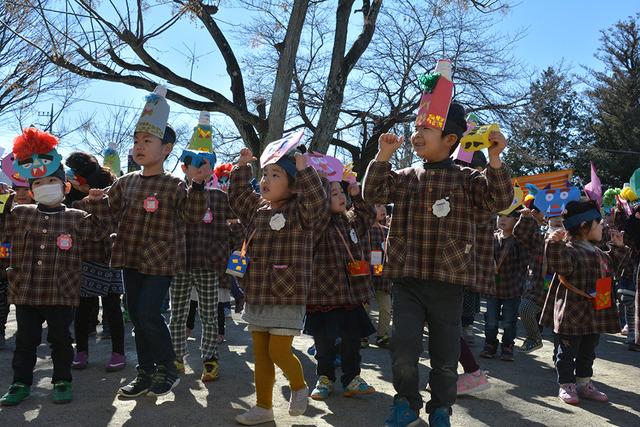 お面を付けて、園庭で鬼の歌のダンスをする園児たちの写真