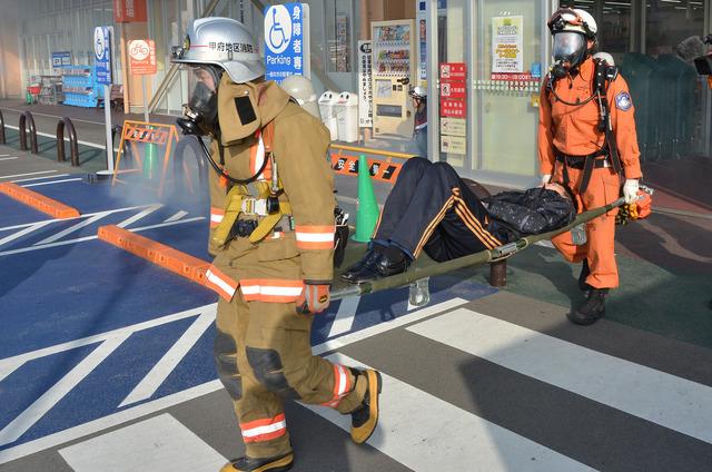 (写真)消防訓練にて消防職員が男性を担架に乗せて運んでいる様子
