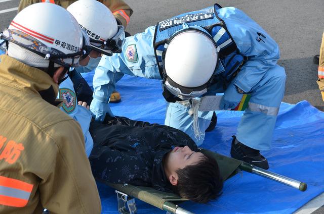 (写真)消防訓練にて負傷者役の男性に消防職員がトリアージを行っている様子