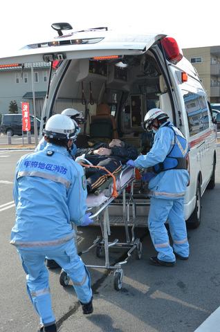 (写真)消防訓練にて消防職員が負傷者役の男性を救急車に乗せている様子