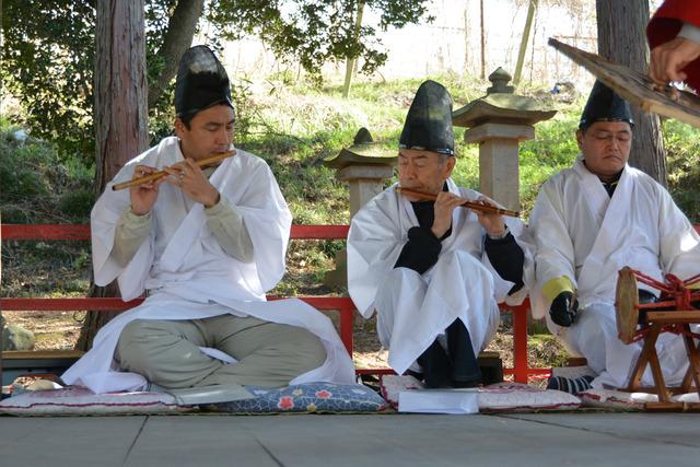 白い衣装を着た男性3人が横笛を太鼓を演奏している写真
