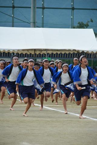 青い法被を着て運動場を走る生徒たちの写真