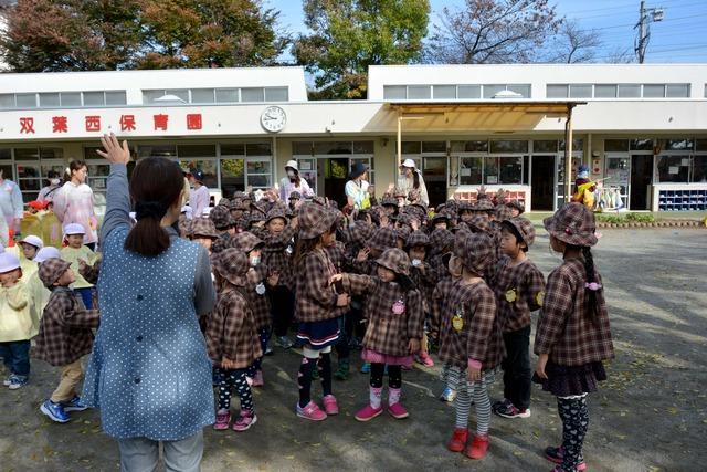 園庭で、園長先生が七五三の由来とお参りの作法の説明している写真