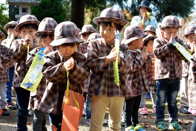 千歳飴を入れる袋を持って、手を合わせる園児たちの写真