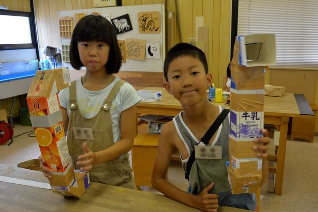 牛乳パックで作った潜望鏡を手に持っている男の子と女の子の写真