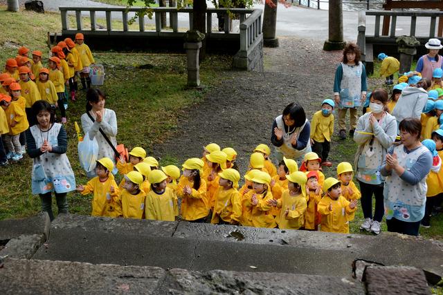 三社神社にて黄色い帽子を被った園児たちが並んでお参りをしている写真