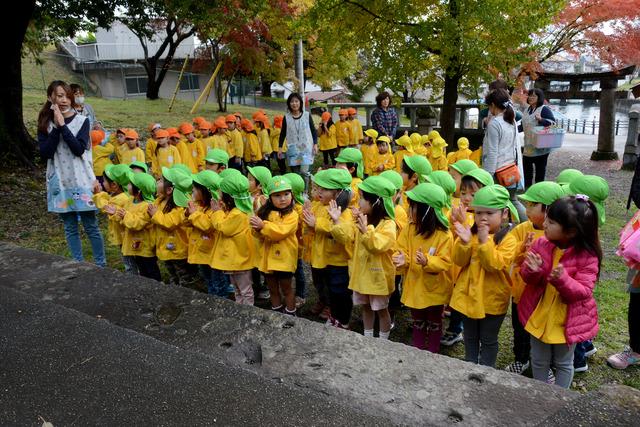 三社神社にて黄緑色の帽子を被った園児たちが並んでお参りをしている写真