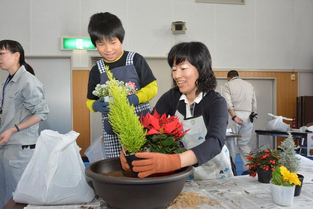 親子が植物を手に取り、鉢の中の位置を決めている写真