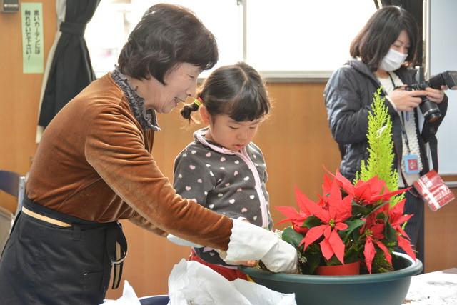 植物を鉢に入れ、位置を決めている女の子の写真