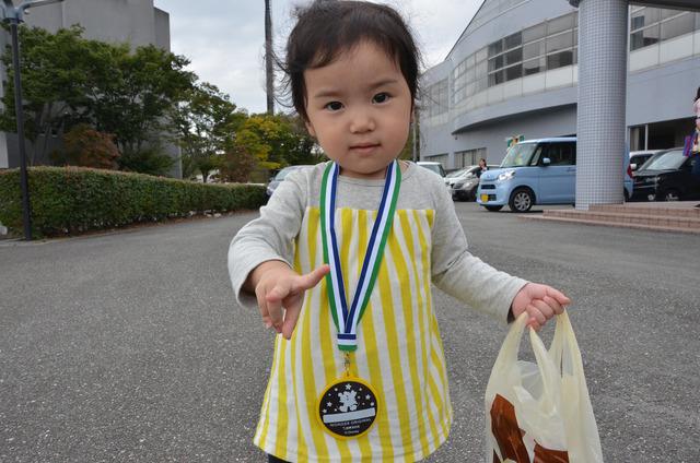 敷島体育館の外でメダルを首からかけた小さな女の子がピースをしている写真