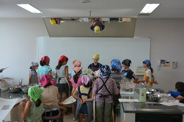 三角巾とエプロンをした子ども達が熱心に中澤さんの説明を聞いている写真
