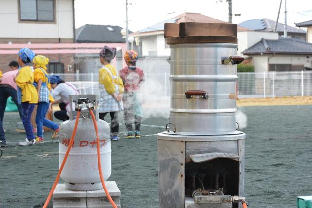 園庭で蒸し器を使いもち米を蒸している写真