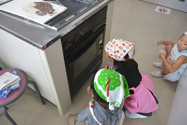 焼きあがりが待ち遠しく、オーブンの中を覗き込むようにみている子ども達の写真