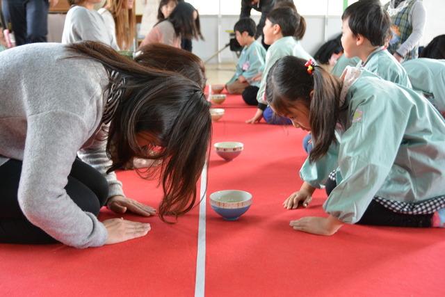 正座でお辞儀をしあう園児と保護者の写真